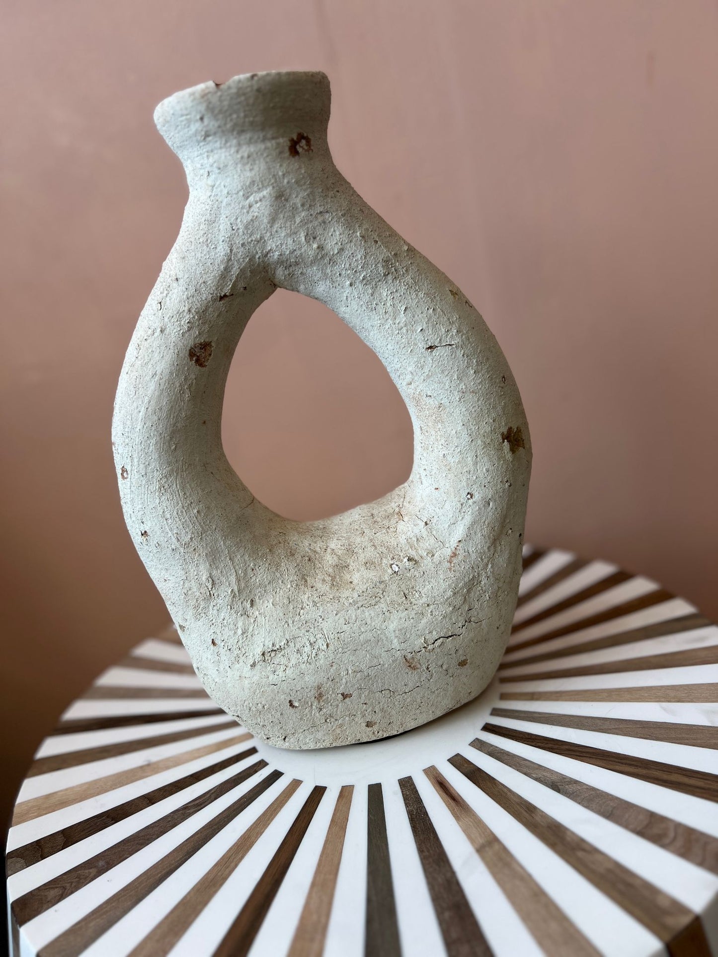 Handgemaakte Marokkaanse vaas gestyled op een houten bijzettafel met natuurlijke accenten."
