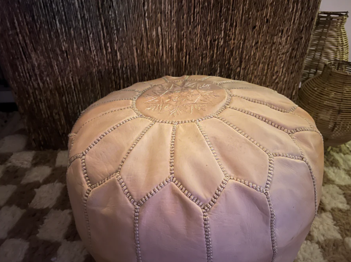 Close-up van de handgestikte details van de leren Ottoman poef in nude kleur.