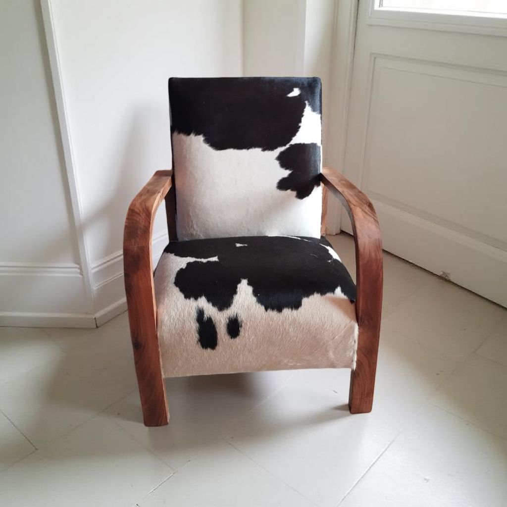 Handgemaakte designstoel van notenhout en koeienhuid tegen witte muur