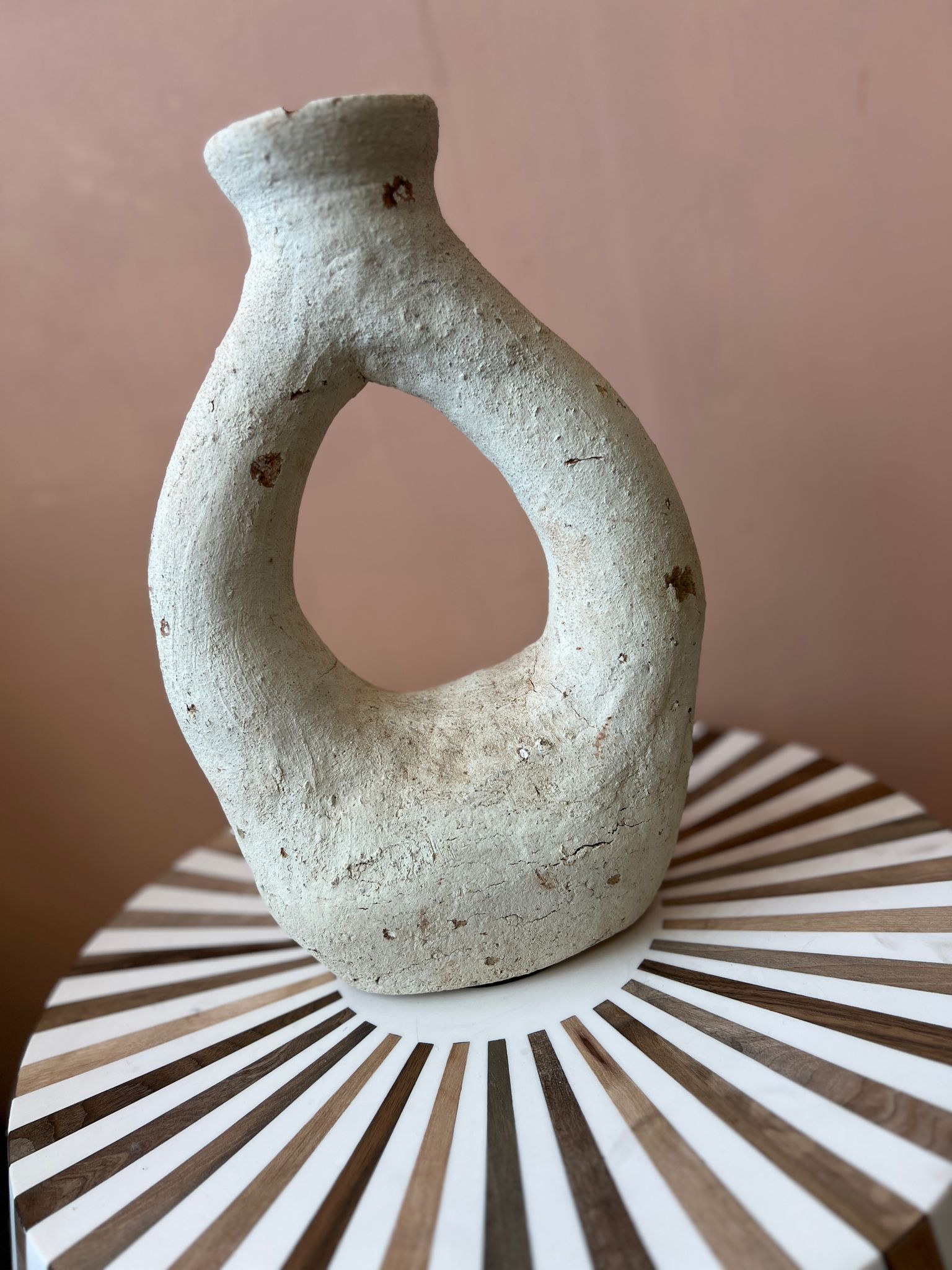 Handgemaakte Marokkaanse vaas gestyled op een houten bijzettafel met natuurlijke accenten."