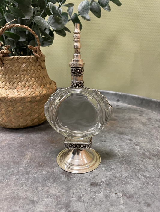 Handgemaakte vintage parfumfles met zilveren details en glazen afwerking.